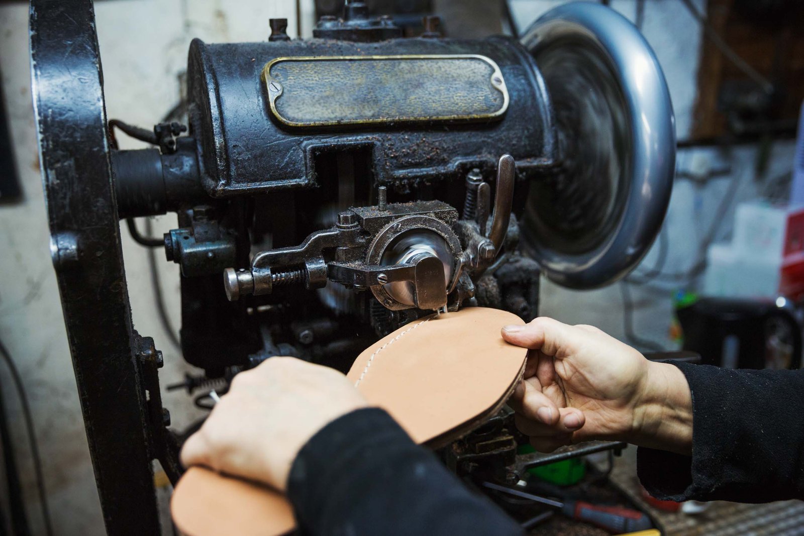 Close up of worker in a shoemaker's workshop, using a machine to sew a leather sole.